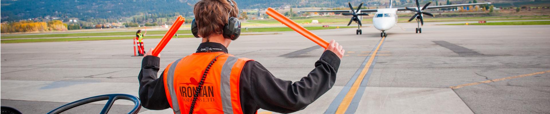 Airfield worker guides in a plane on a sunny day